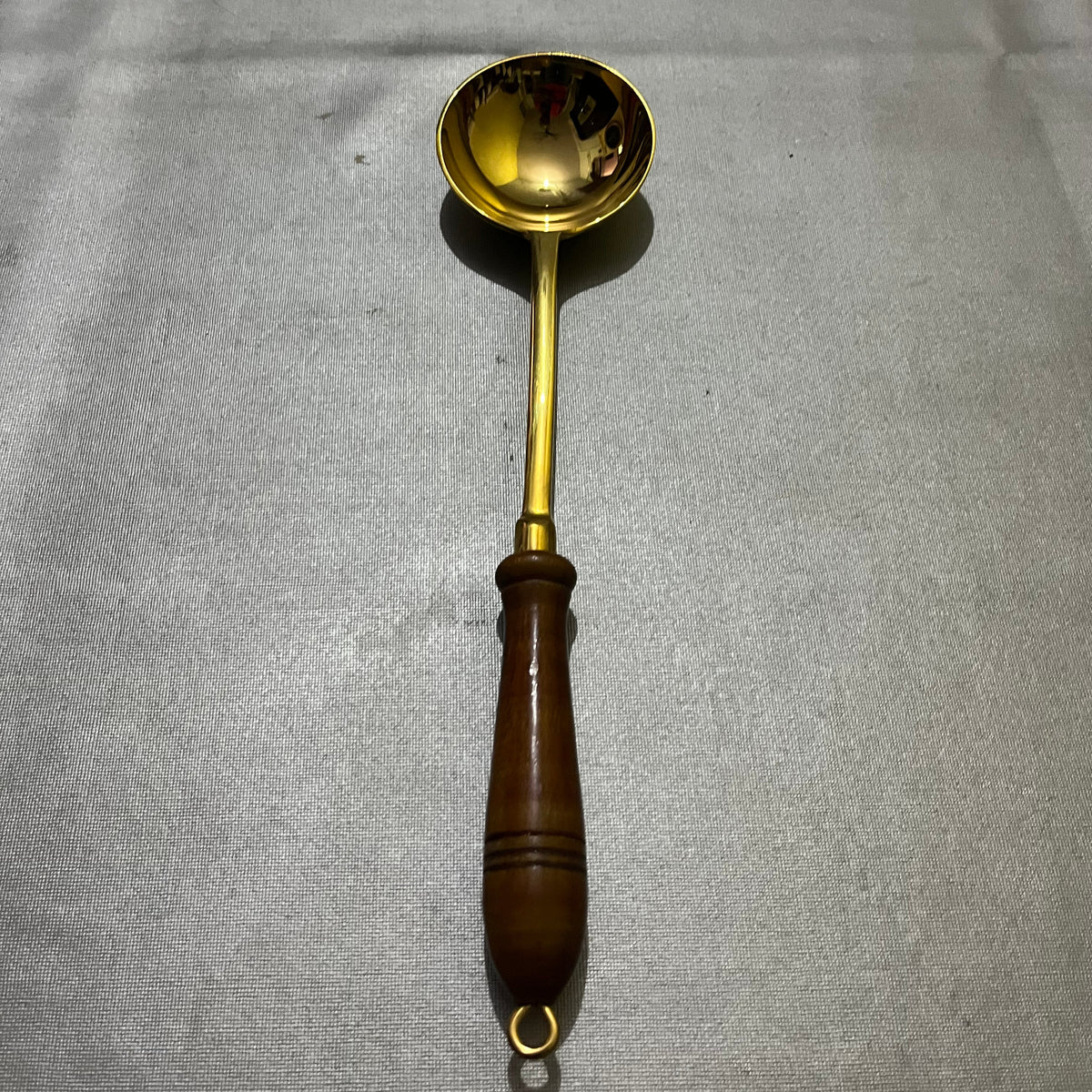 brass ladle with a long wooden handle 