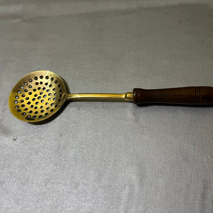 brass slotted ladle with a dark brown wooden handle.